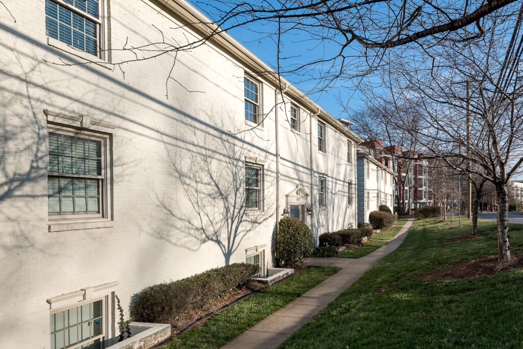 Front view of a white brick multifamily residential property with 2 to 4 units and well-kept landscaping.