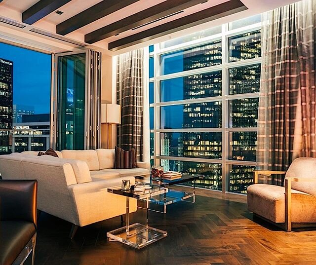 Modern high-rise apartment living room with floor-to-ceiling windows and a city skyline view at dusk.